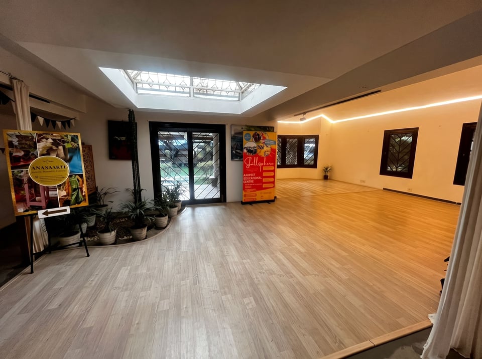The skylit gallery room at Namma Ashram with artwork on the walls and a wooden floor