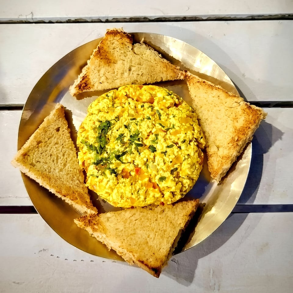A bhurji served with triangles of toast on a brass plate
