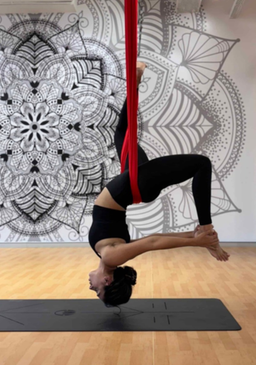 Aerial yoga inversion in a red silk hammock
