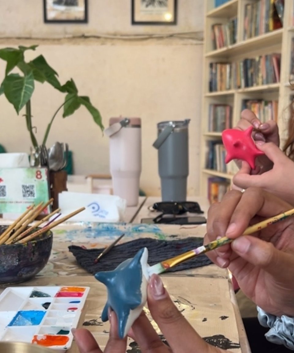 Hands painting clay pieces at a craft table