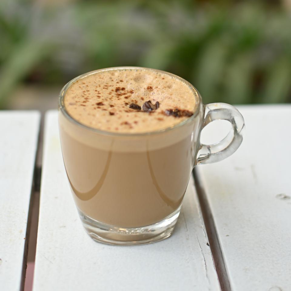 A glass cup of coffee on a white café table